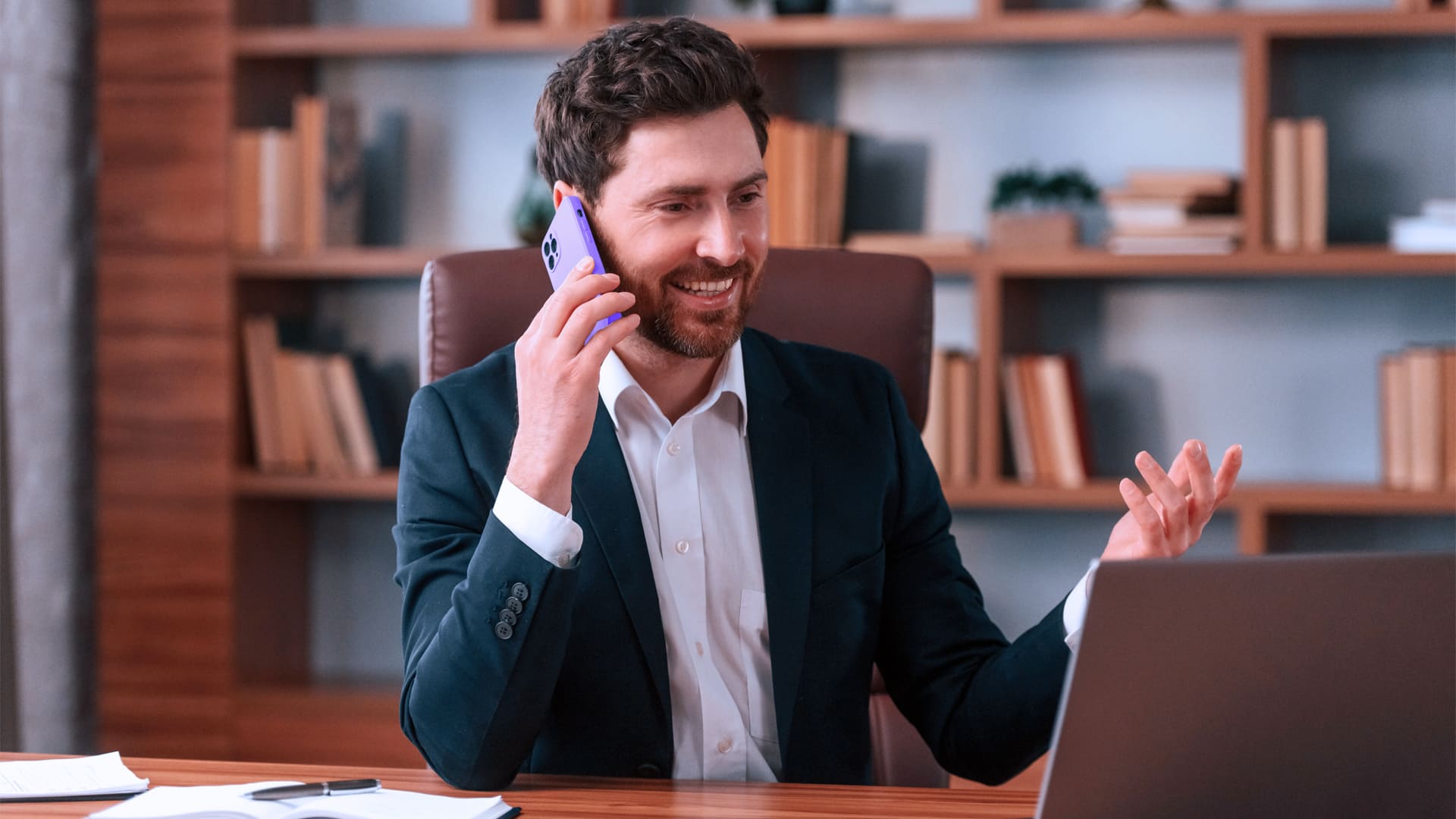 Empresario joven sonriendo manteniendo una conversación por teléfono móvil
