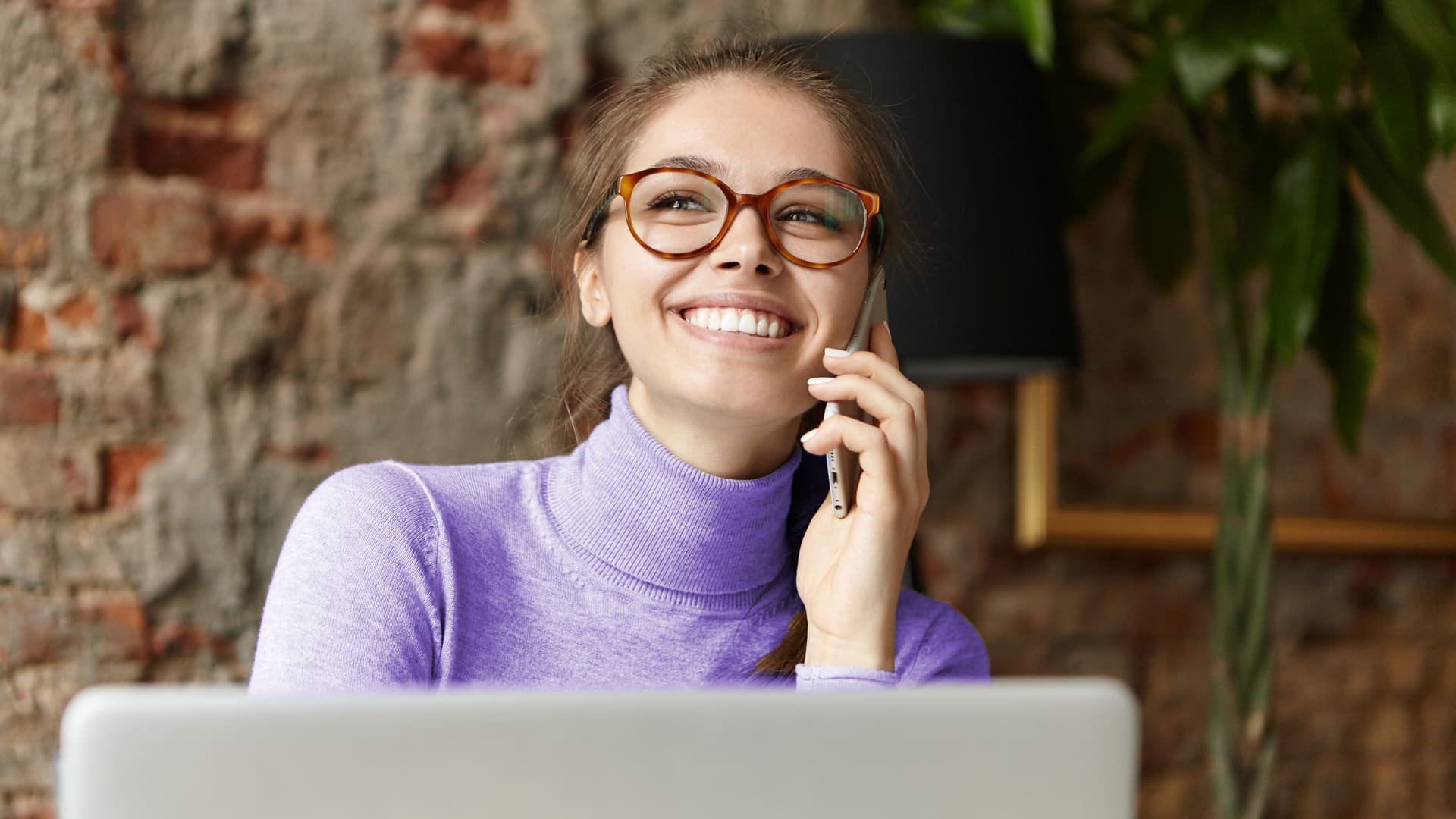 Mujer empresaria joven atendiendo una llamada telefónica desde su domicilio