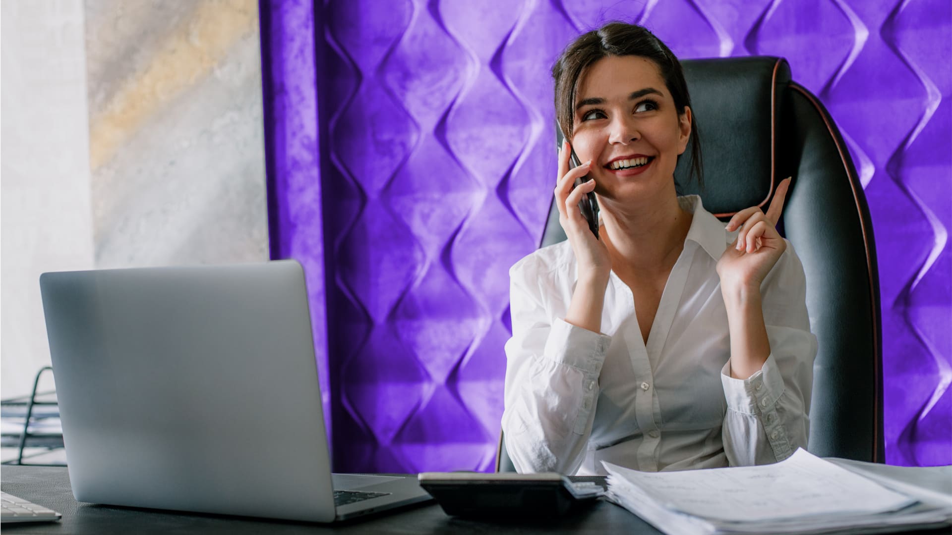 Mujer empresaria trabajando en su escritorio atendiendo una llamada telefónica desde su móvil