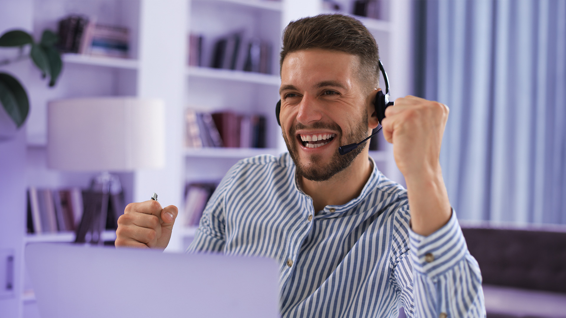 Supervisor de contact center sonriendo mientras teletrabaja desde casa y monitoriza a su equipo