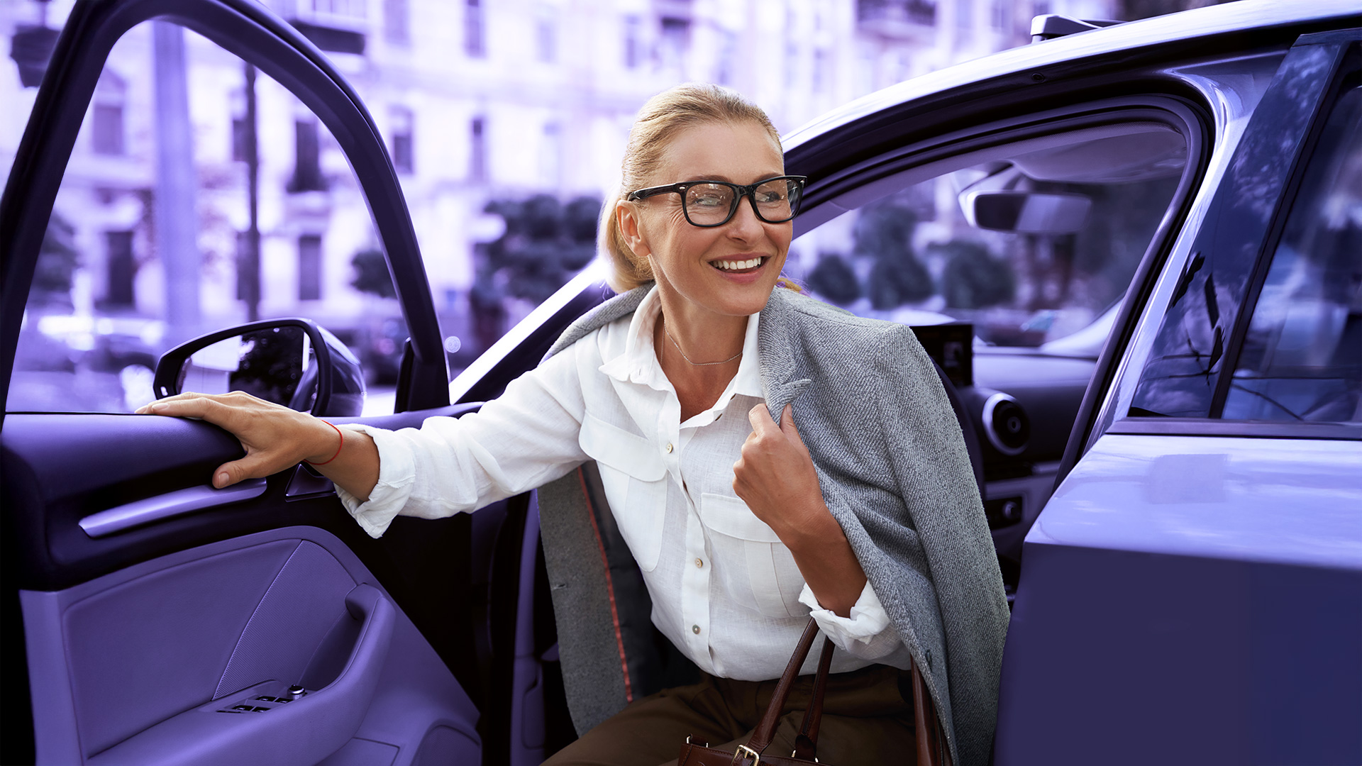 Mujer comercial saliendo del coche sonriendo con una mano en la puerta