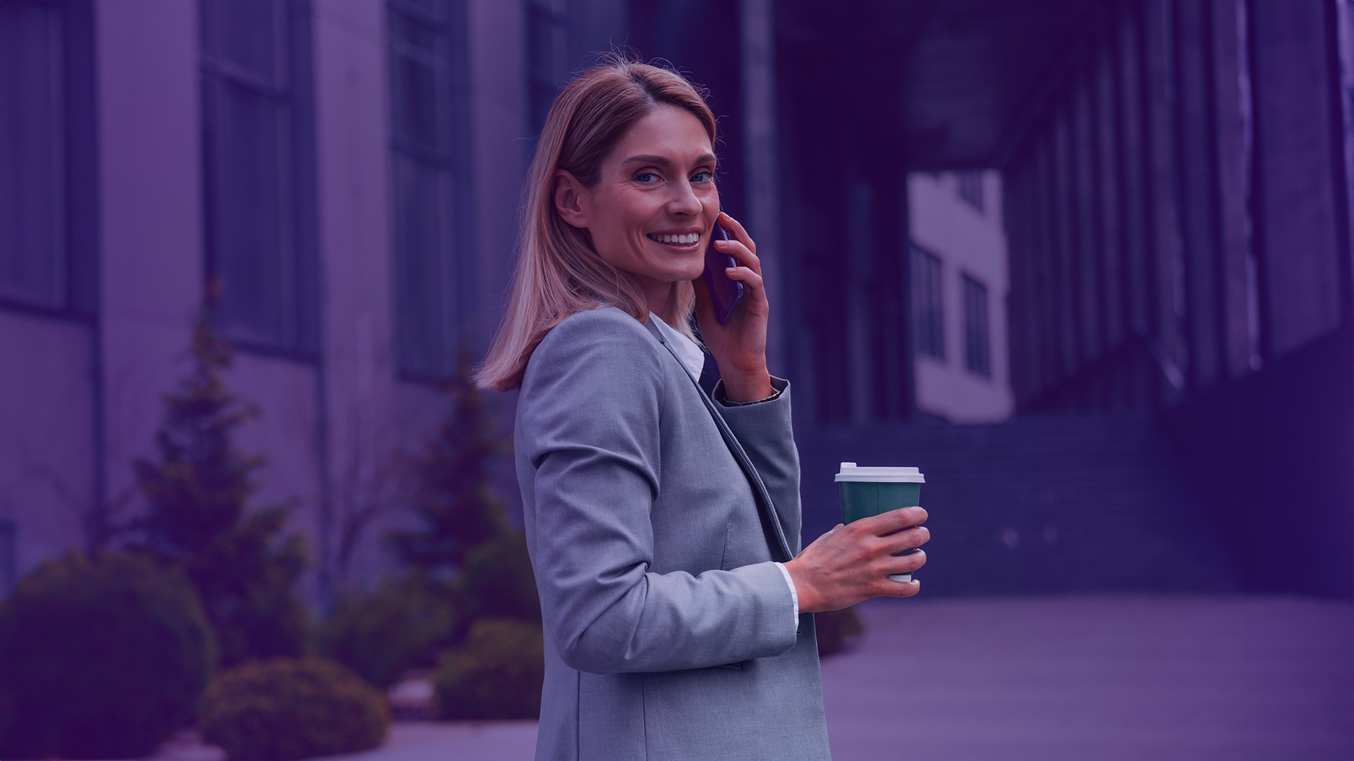 Mujer empresaria que trabaja en un banco tomando café y haciendo una llamada desde su móvil grabándola con Smart Mobile by Enreach