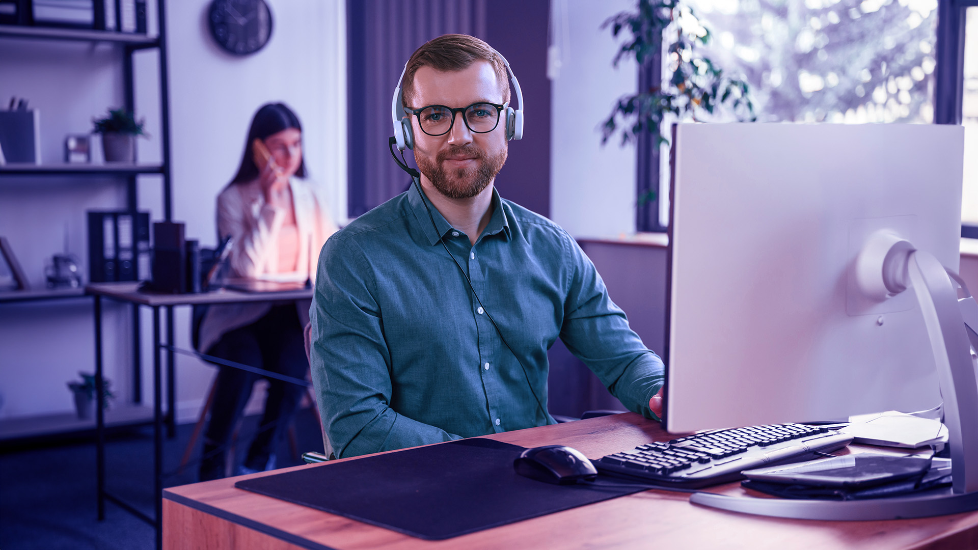 Hombre agente outbound en su oficina delante del ordenador con auriculares llamando a clientes con software Enreach