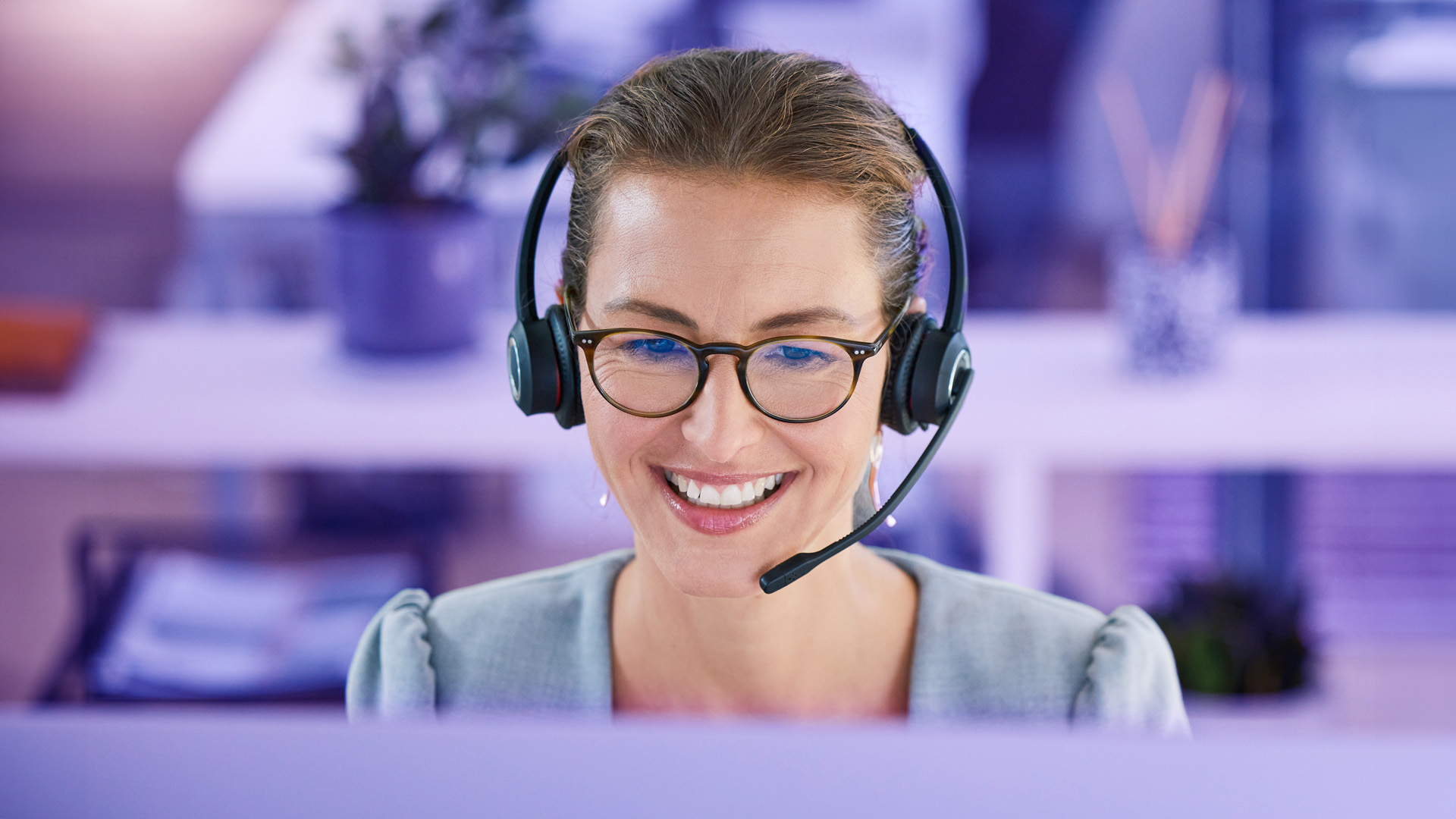 Mujer agente de contact center sonriente mientras atiende llamadas inbound y outbound gracias al call blending